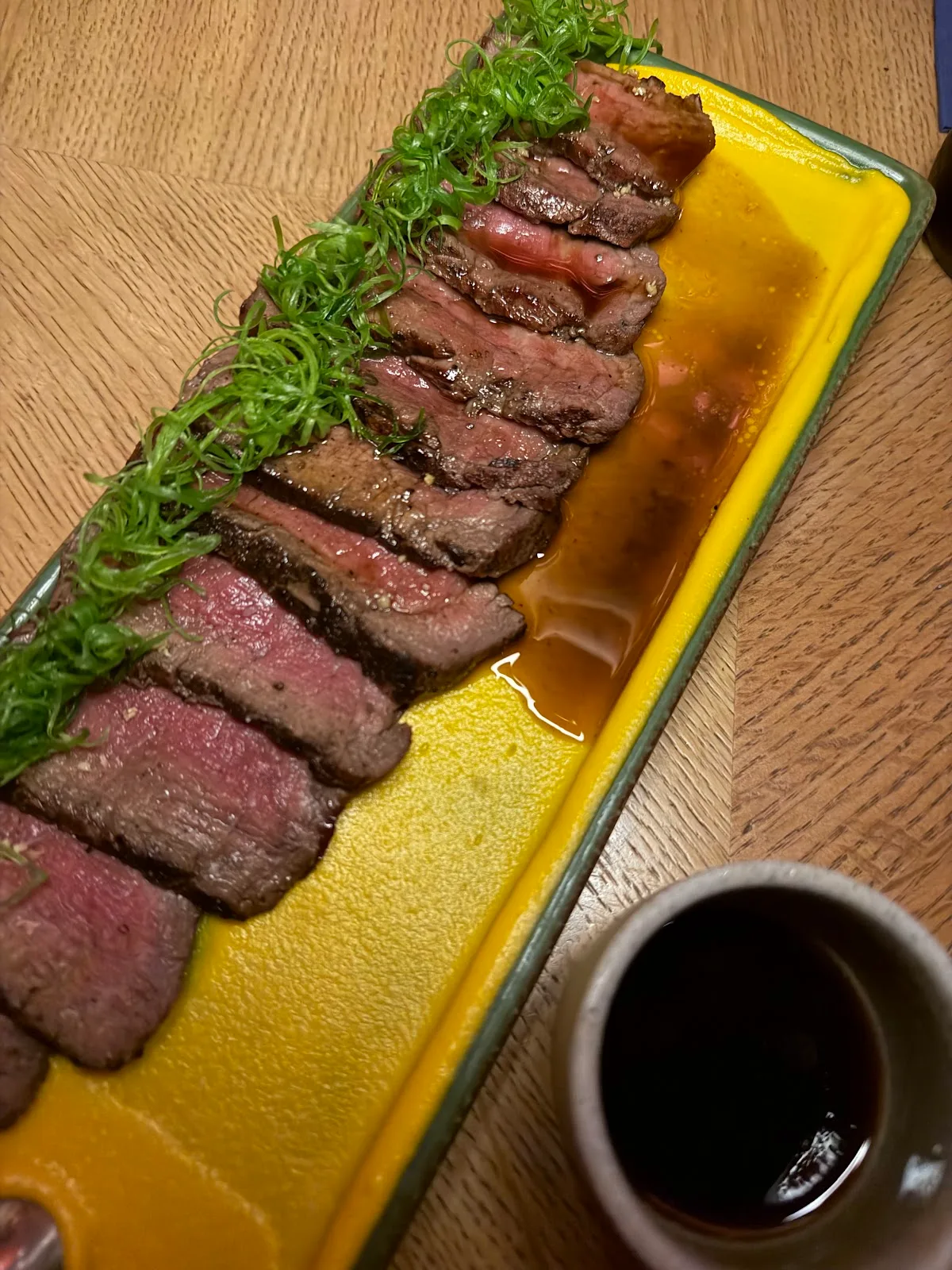 Sliced charcoal-grilled steak on a yellow sauce