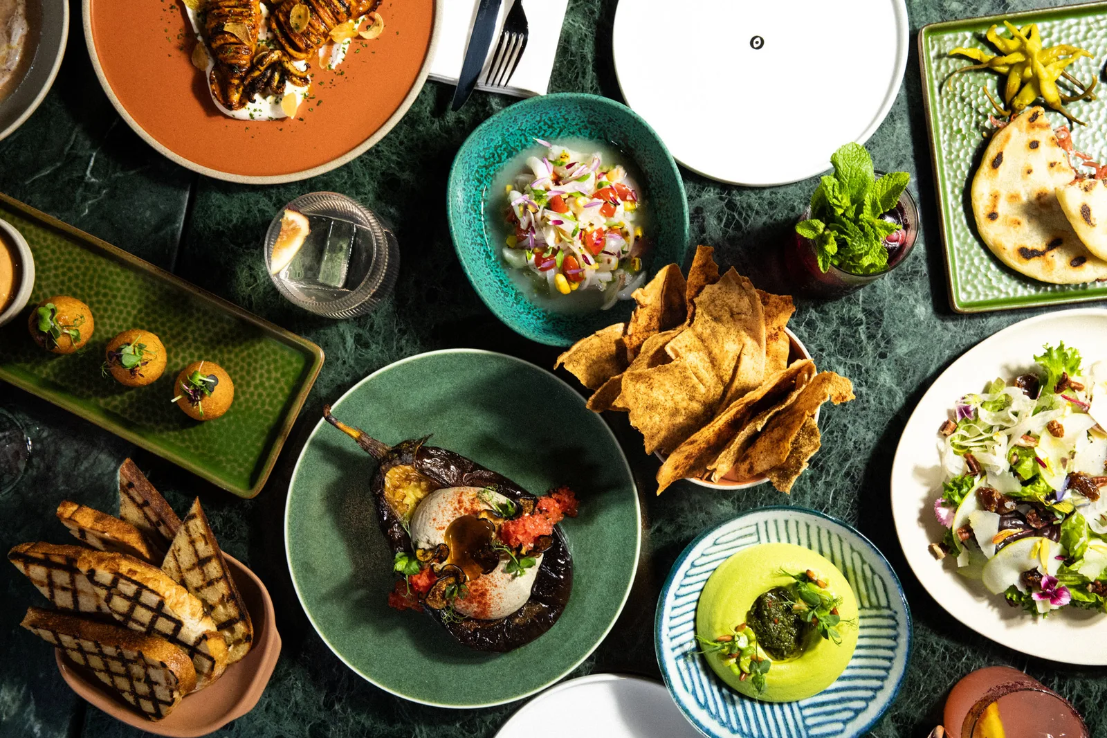 An overhead spread of colourful sharing dishes on a green marble table at Soul Kitchen Dubai