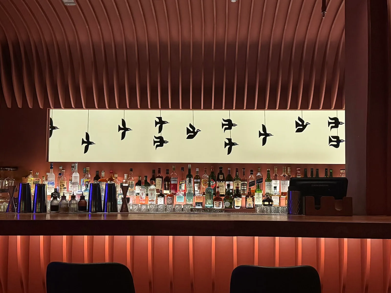 The bar at Soul Kitchen with a flying-birds light panel above the bottles
