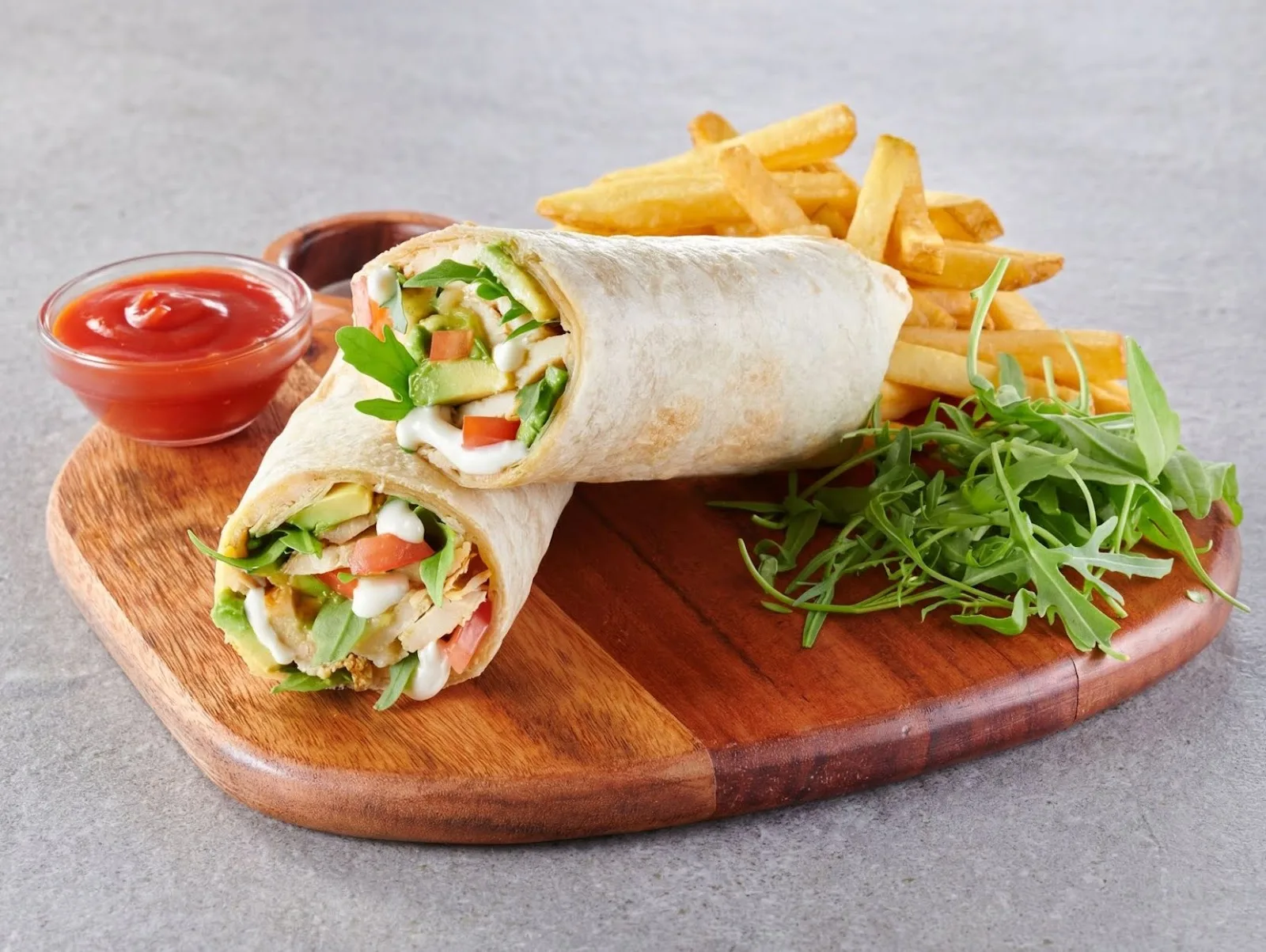 Chicken wrap with fries on a wooden board