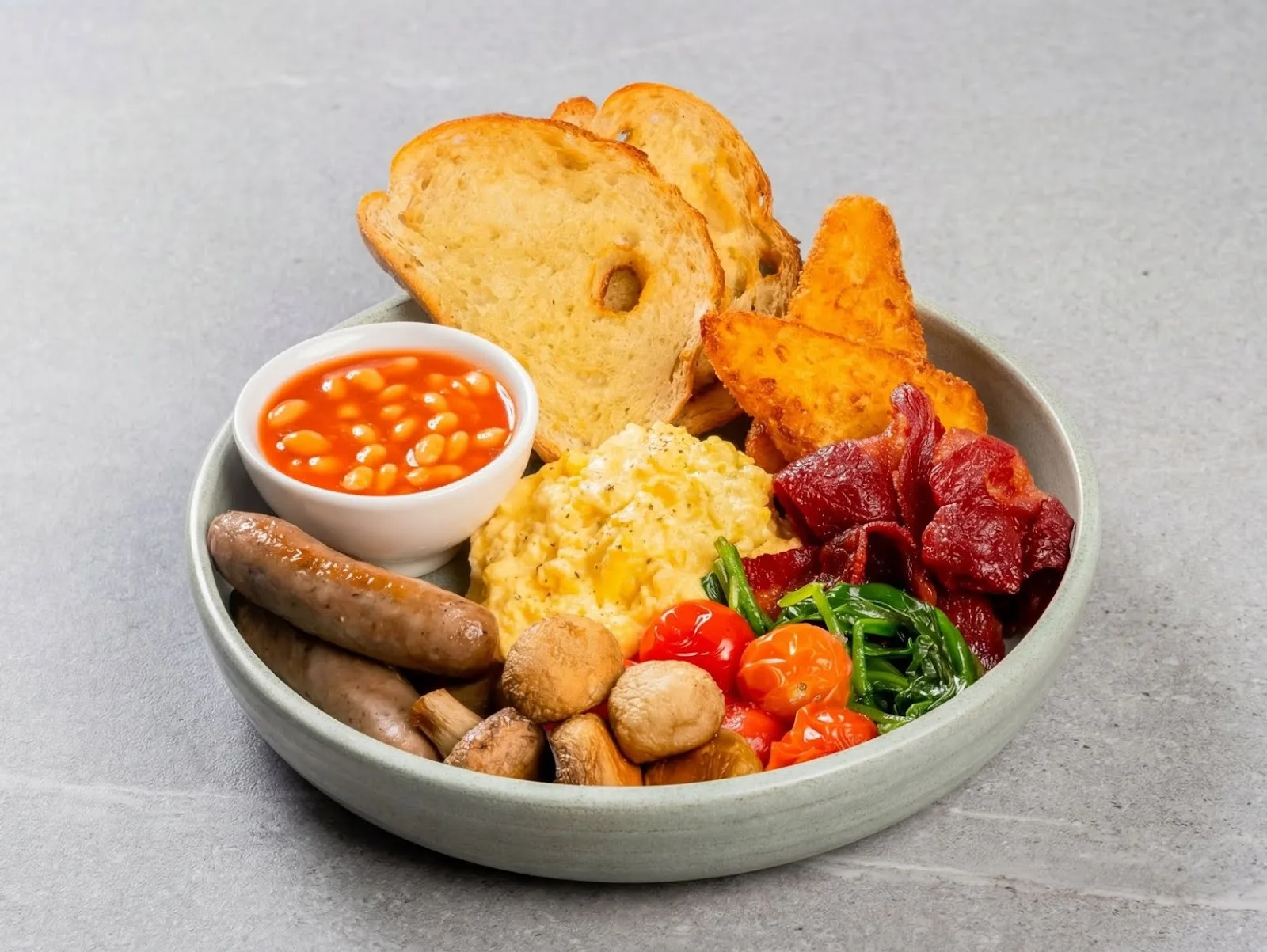 A full breakfast plate with eggs, sausages, bacon and beans