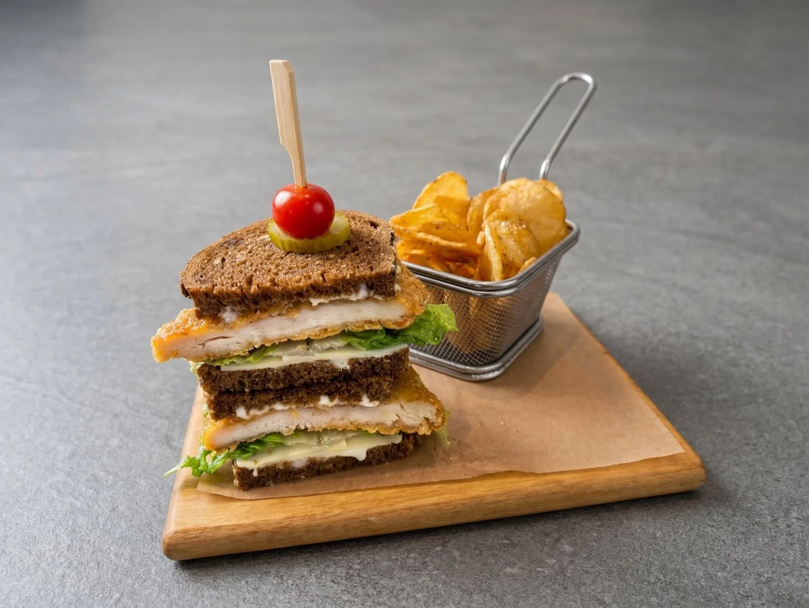 Stacked club sandwich with a basket of chips