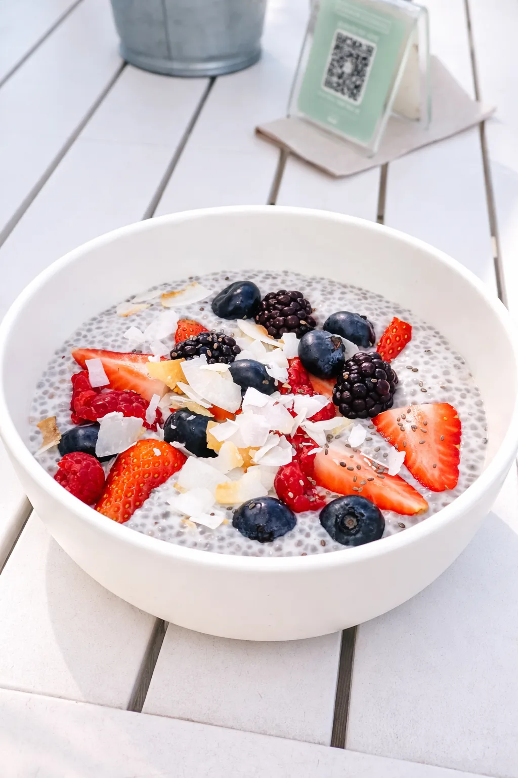A chia pudding bowl topped with berries and coconut flakes
