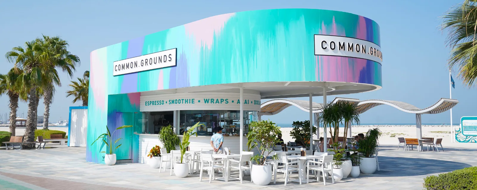 The colourful Common Grounds café framed by palms on a clear day