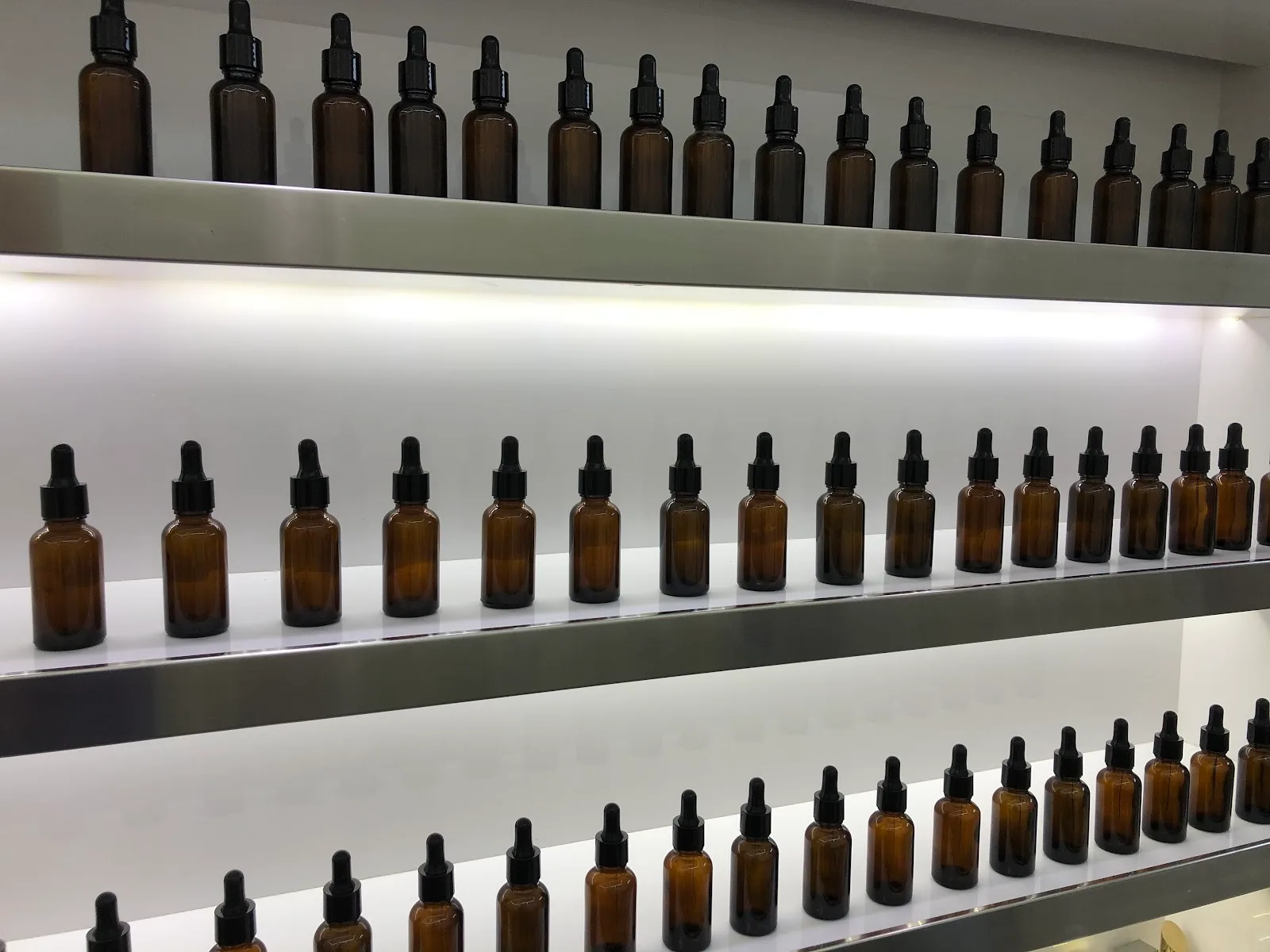 Rows of amber dropper bottles on lit shelving