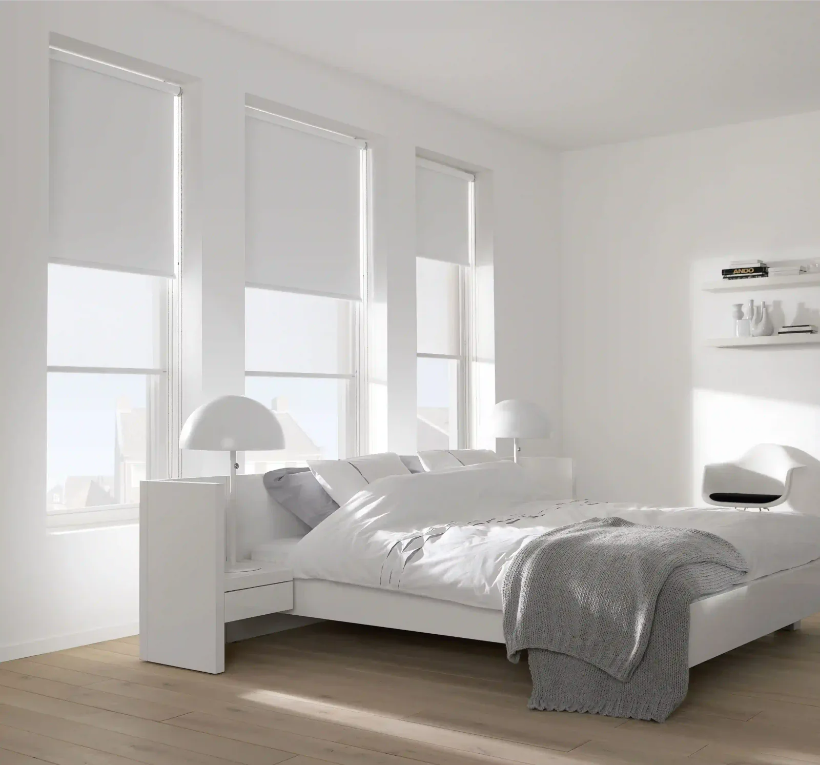 White roller blinds across three windows in a minimal bedroom