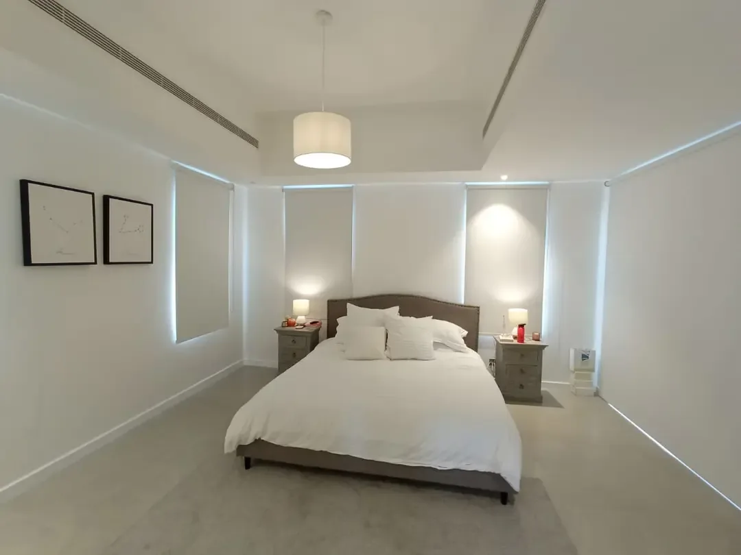 Roller blinds behind a bed with warm lamp light