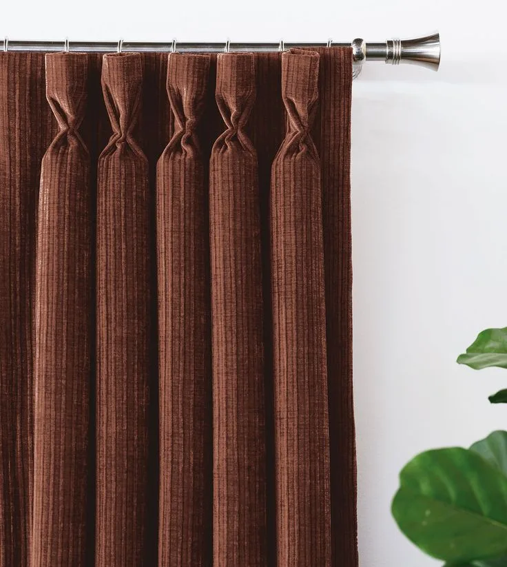 Rust-toned pinch-pleat curtains hung from a steel pole