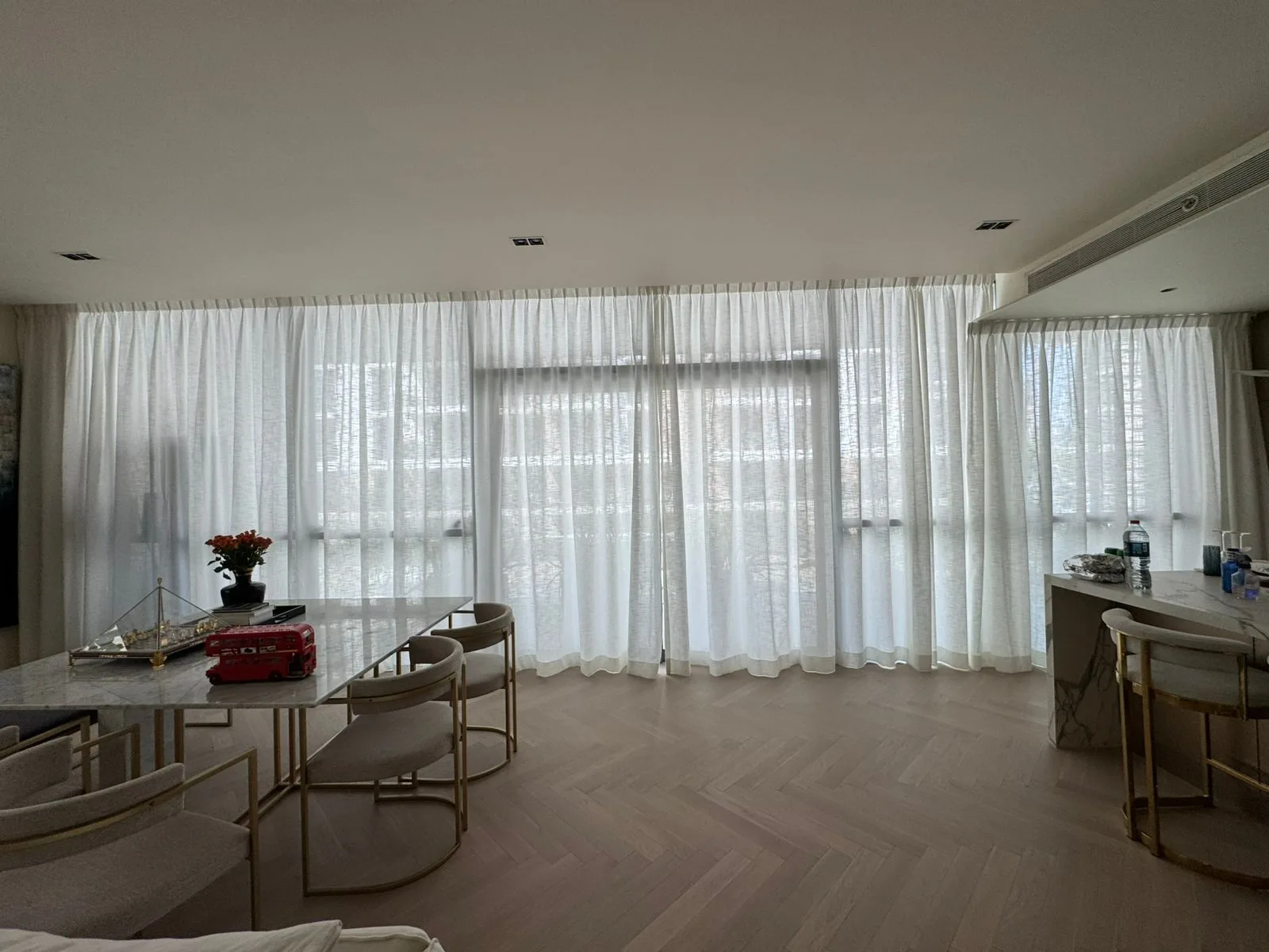 Sheer curtains in a dining room with herringbone wood floor