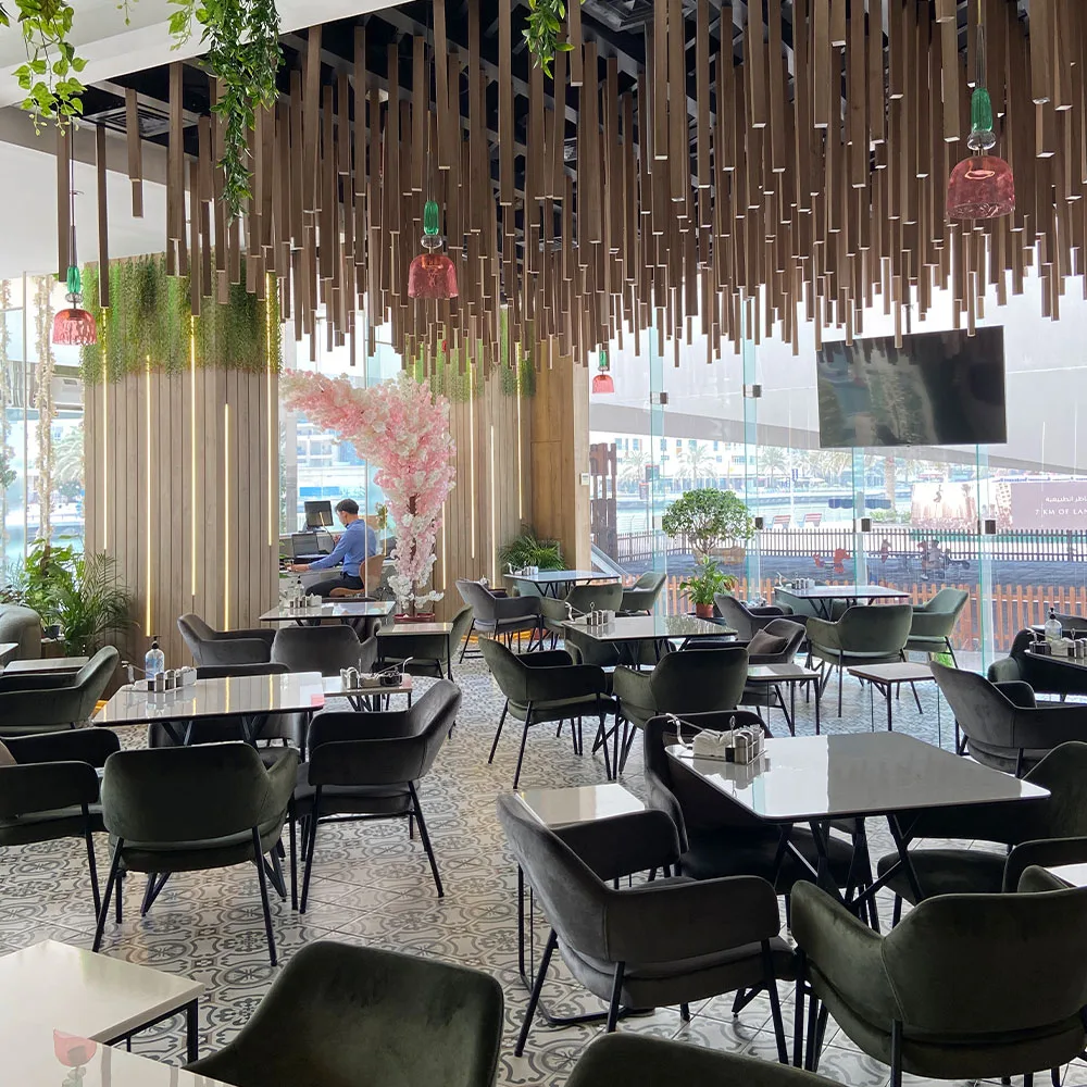 Wide view of the café dining area with hanging-stick ceiling and marina windows
