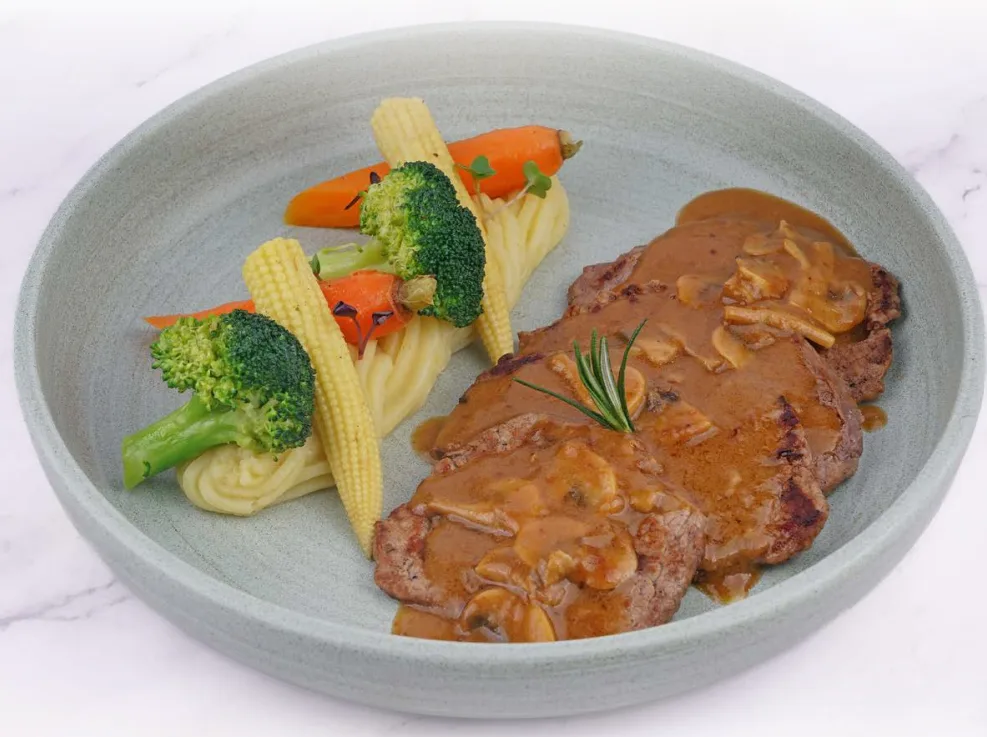 Grilled steak plated with vegetables and sauce