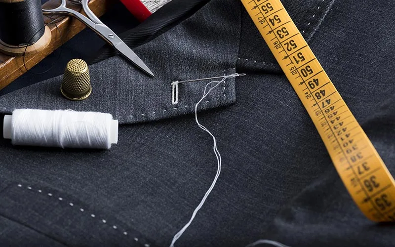A tailored navy suit on a form with a measuring tape, ready for alteration