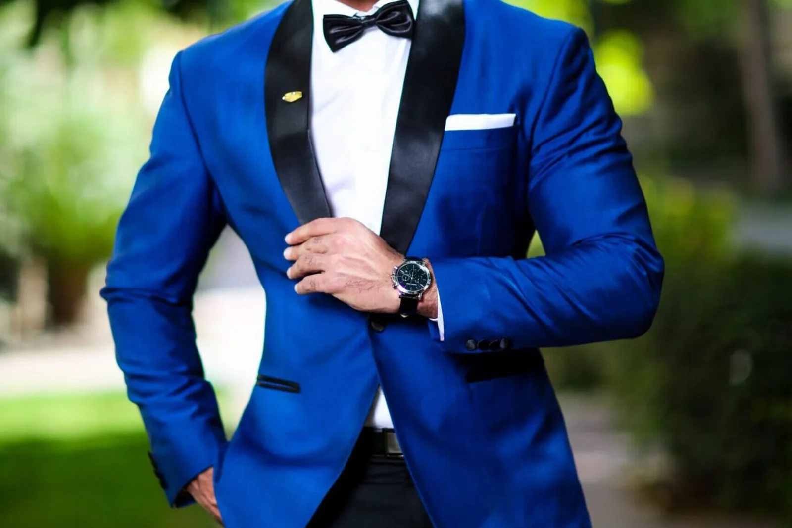 A man in a sharply tailored blue dinner jacket and bow tie