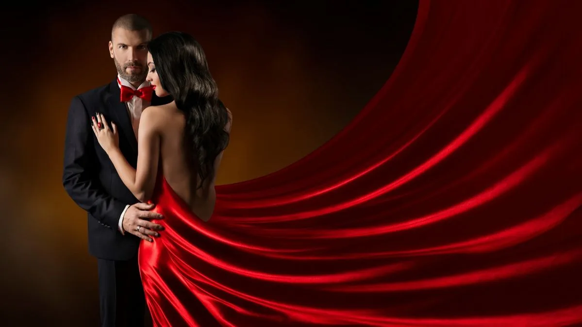 A couple in formal wear with flowing red silk fabric