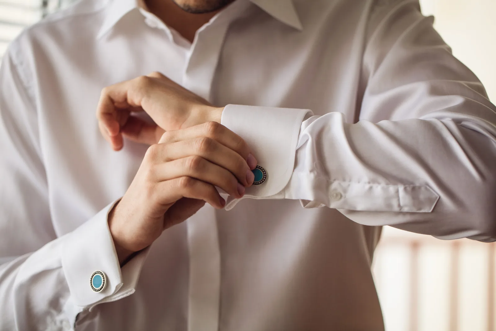 A man fastening cufflinks on a crisp white dress shirt