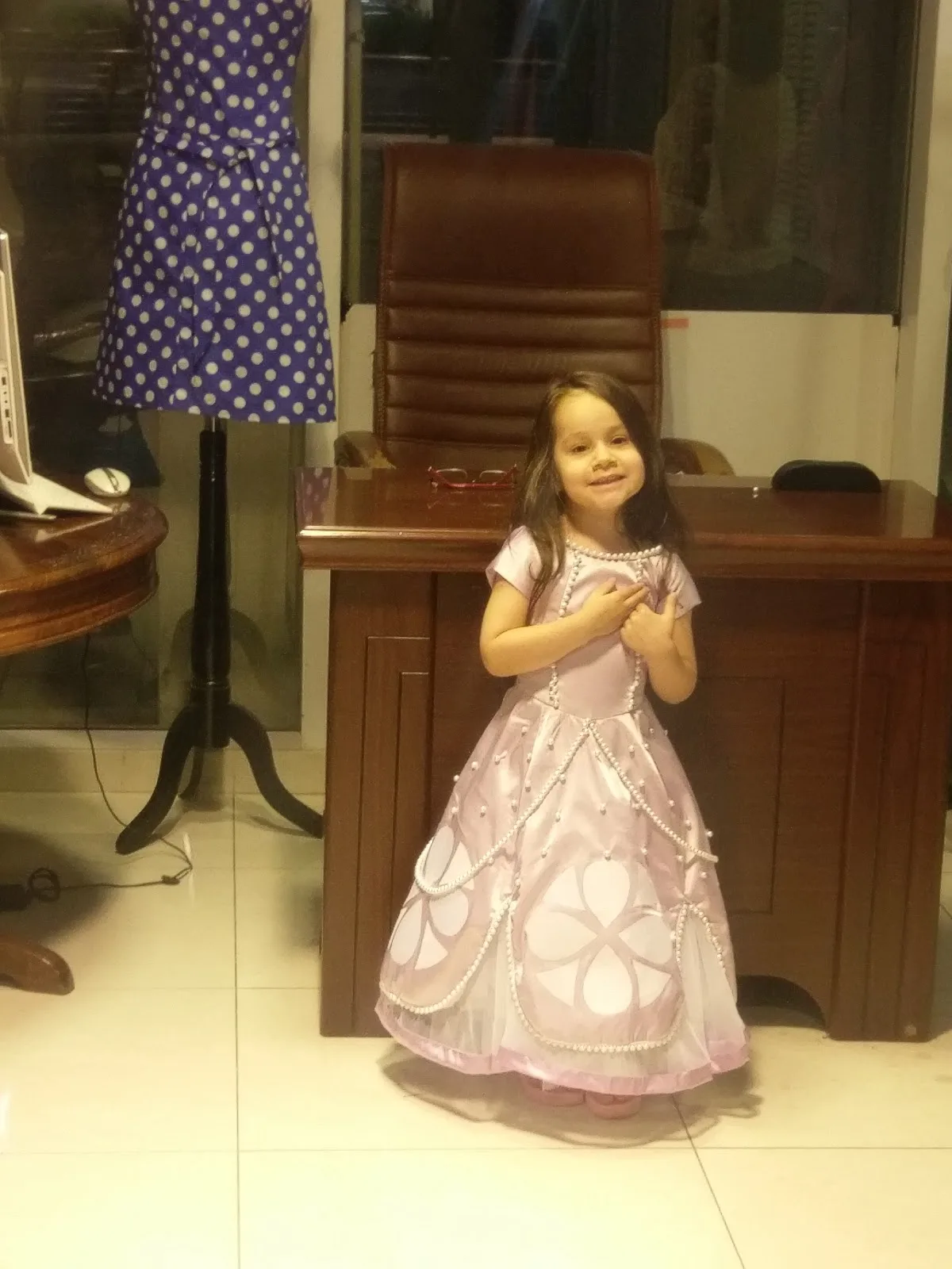 A young girl in a pearl-trimmed pink party dress made at the shop