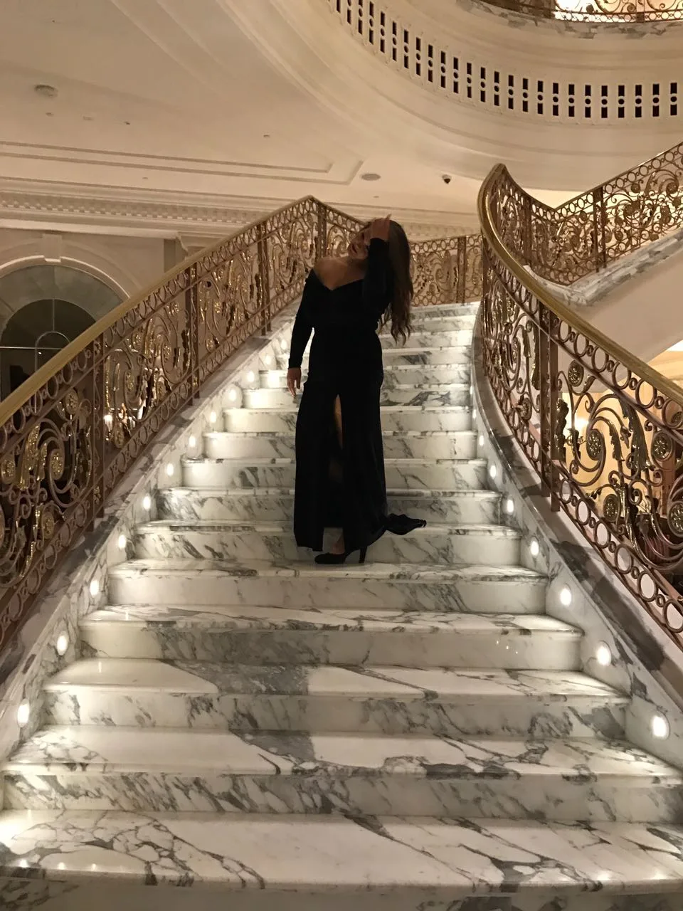 Client in a long black evening dress on a marble staircase