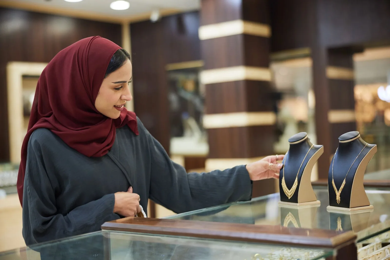 A customer viewing gold necklaces displayed on stands at the Anjali Jewellers counter in Deira, Dubai