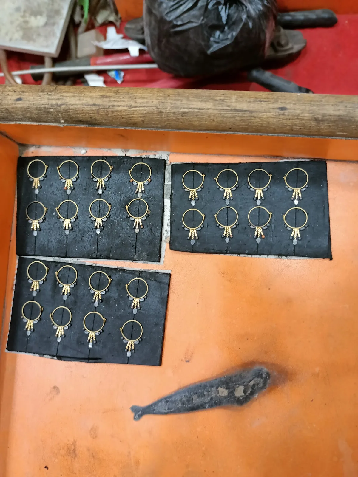 Rows of handcrafted gold earrings prepared on trays in the workshop