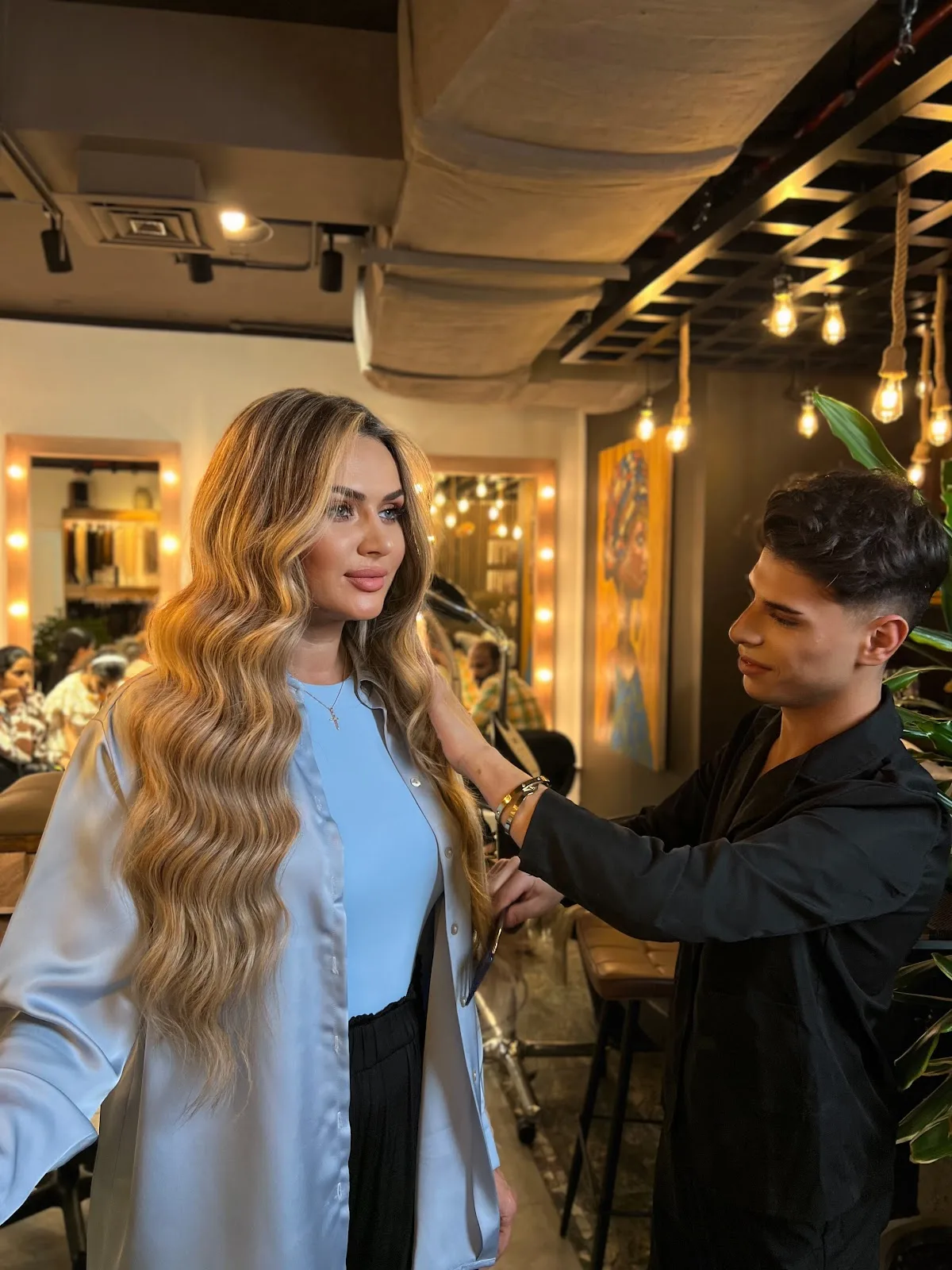 A Paulista stylist finishing a client's long, glossy waves in the salon