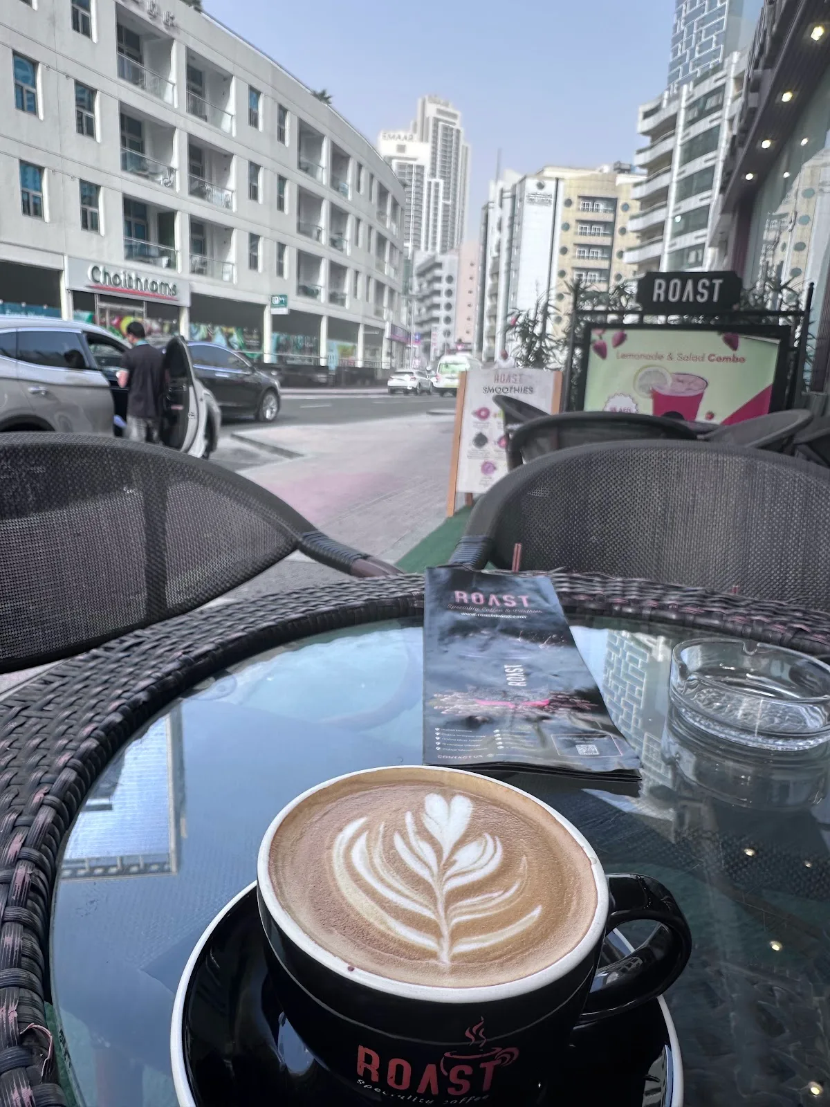 A latte on an outdoor table with the Dubai Marina street beyond