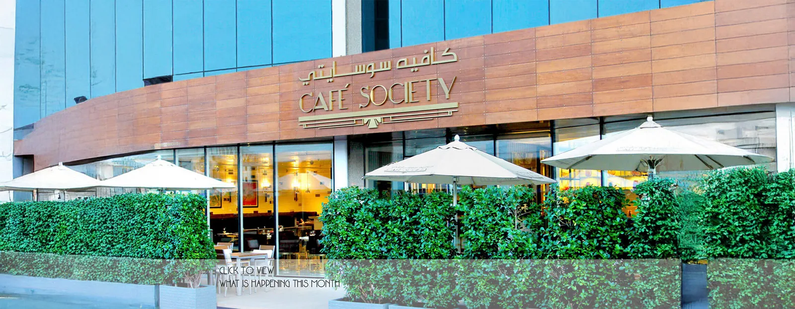 Café Society storefront with hedges and umbrellas