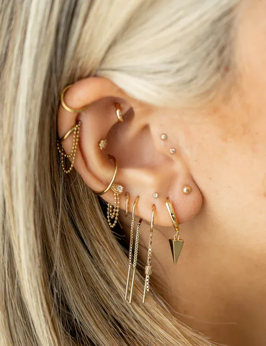Stacked gold earrings and threader along a curated ear
