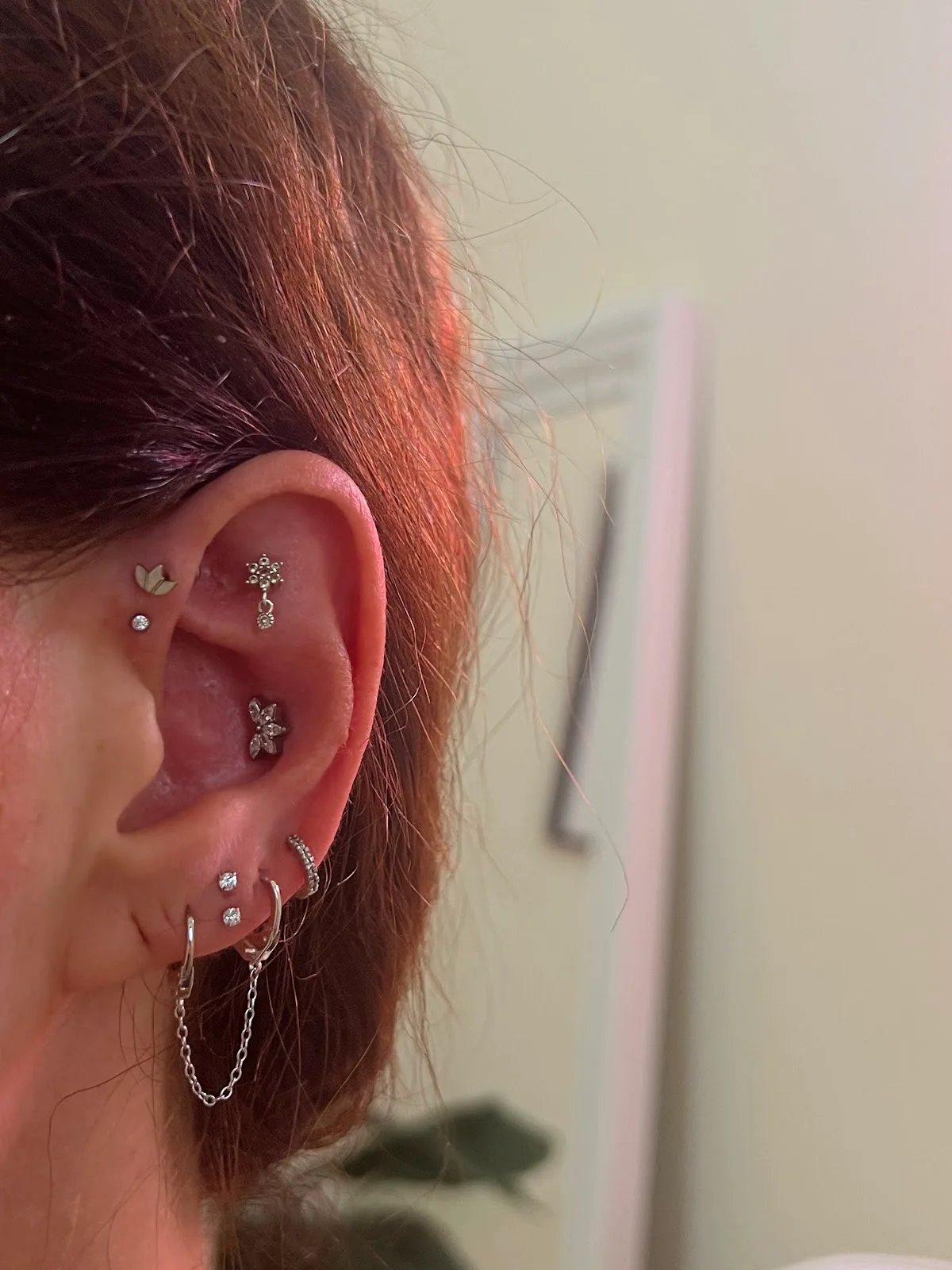 Close-up of a styled ear with several lobe and helix piercings