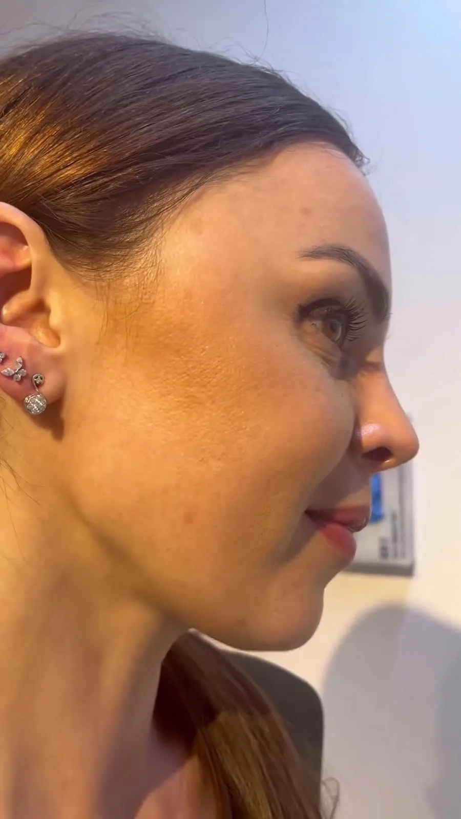 Profile of a client with a curated cluster of silver and crystal ear piercings