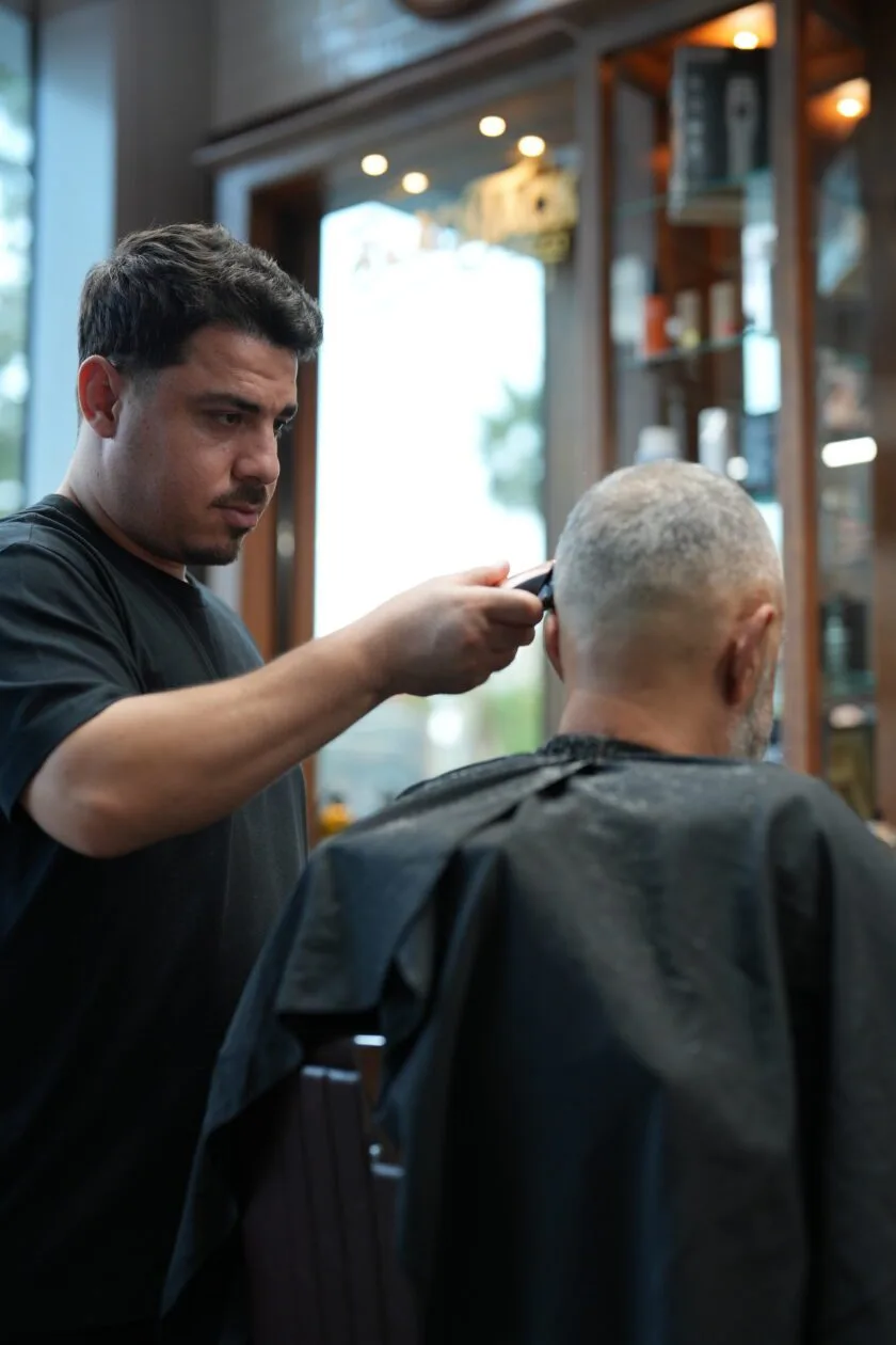 Barber using clippers on a client in the vintage barbershop