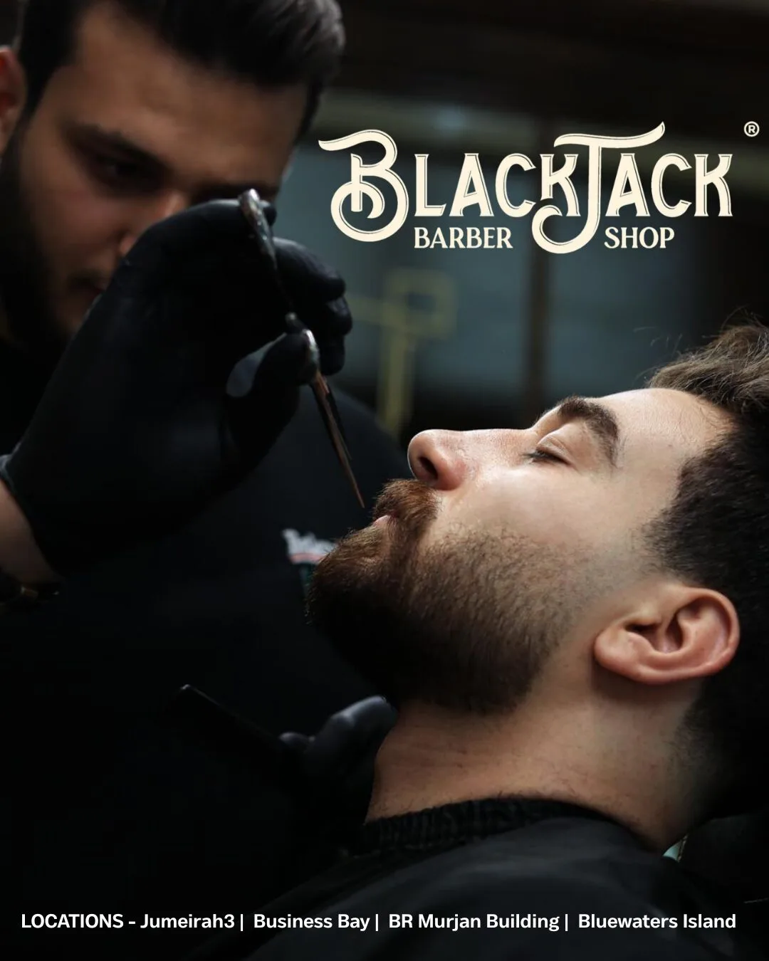 Barber detailing a client's beard with a straight razor at Black Jack