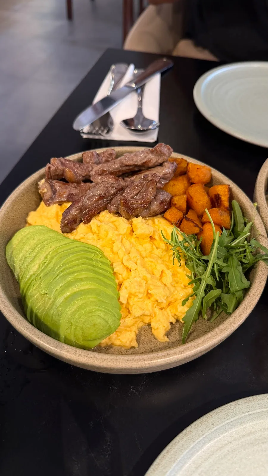 A warm breakfast bowl with greens, eggs and toast