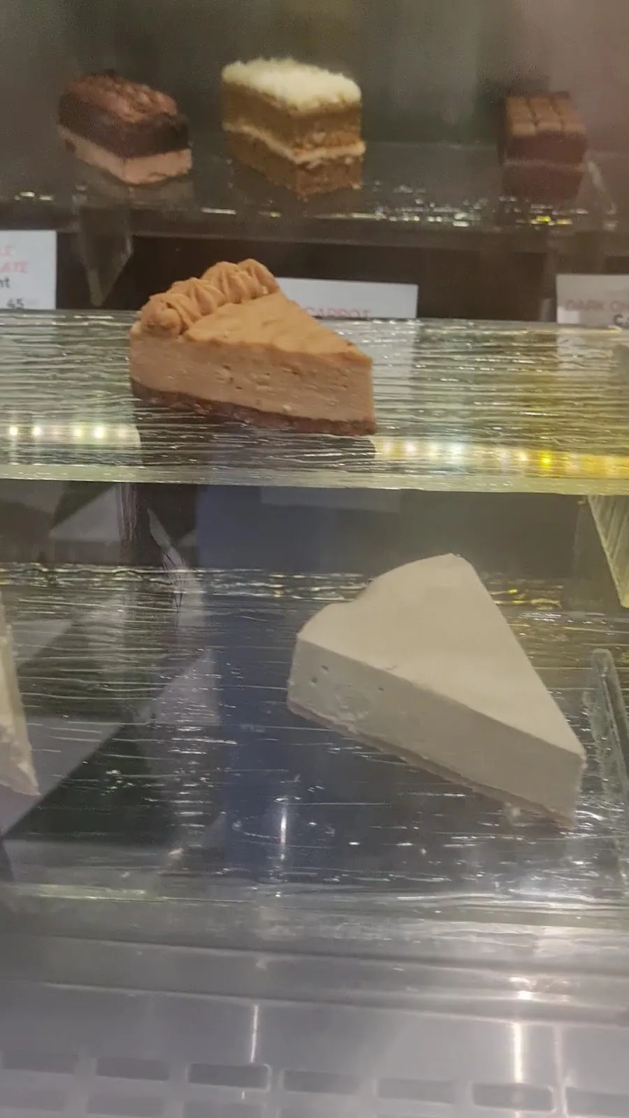 Slices of cake and cheesecake in a glass display cabinet
