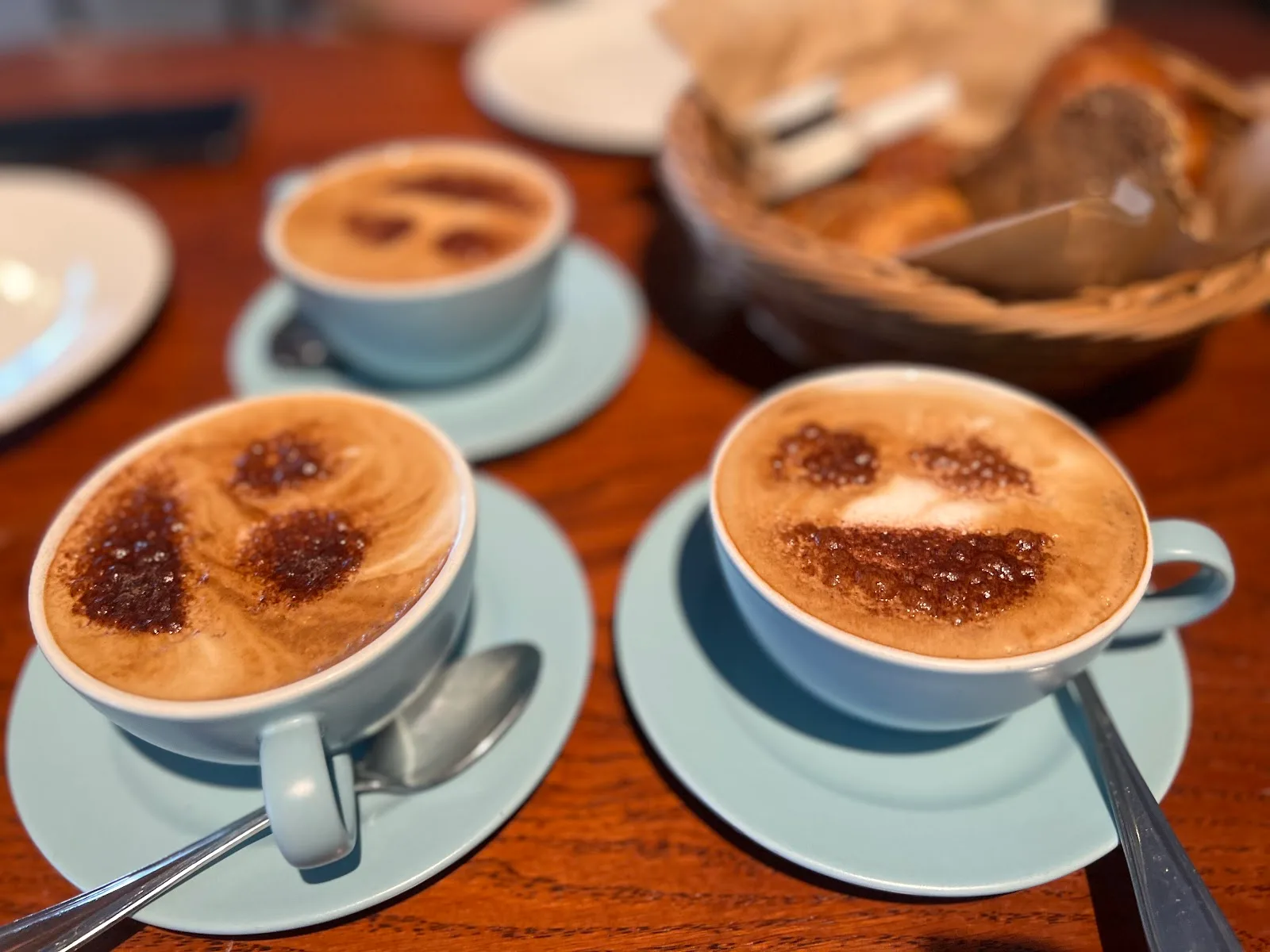 Three cappuccinos with dusted foam art on blue saucers