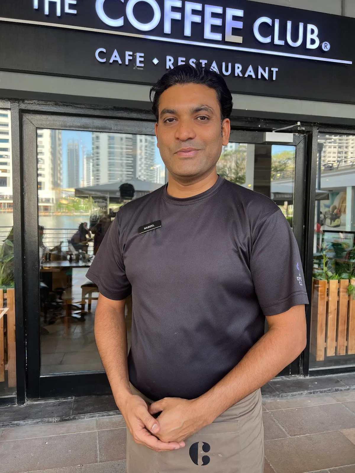 A member of The Coffee Club team standing in front of the cafe entrance