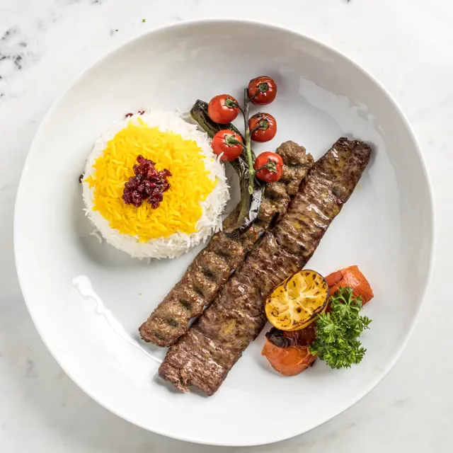 Koobideh kebab with saffron and plain rice on a white plate