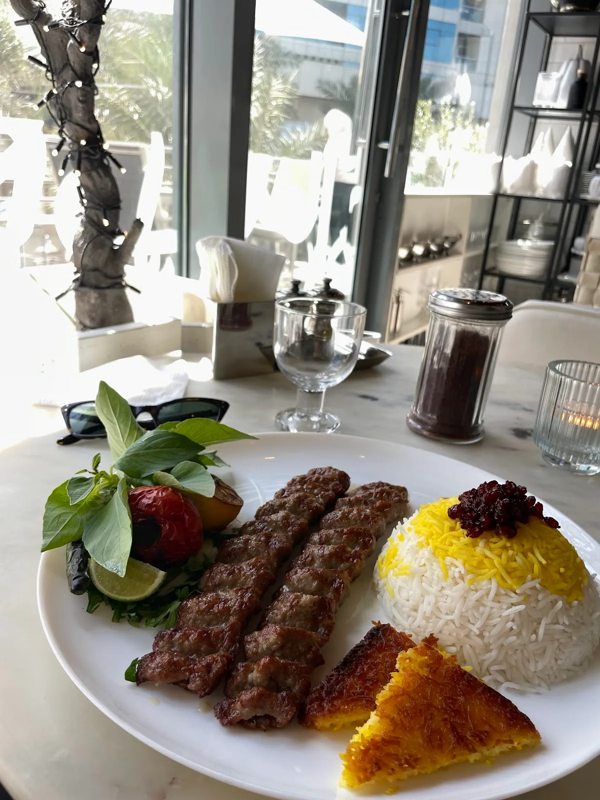 Koobideh kebab plate with saffron rice and tahdig at a Sofreh table