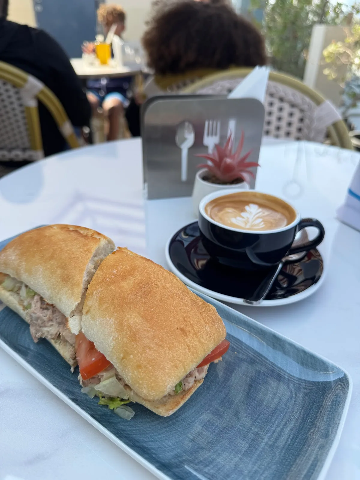 Toasted sandwich on a blue plate next to a flat white