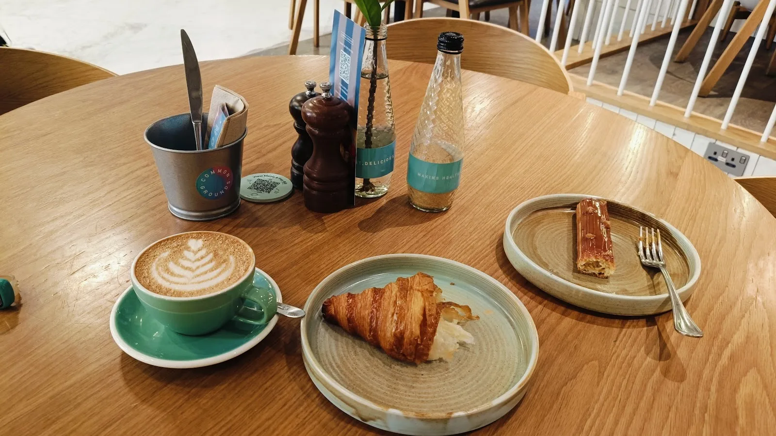 Cappuccino, croissant and a pastry set on a round wooden table