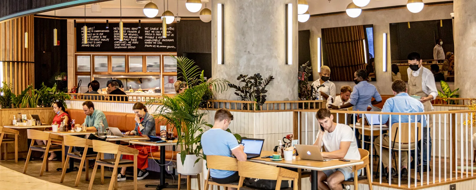 Café interior with a handwritten chalkboard about the coffee programme and diners working at tables