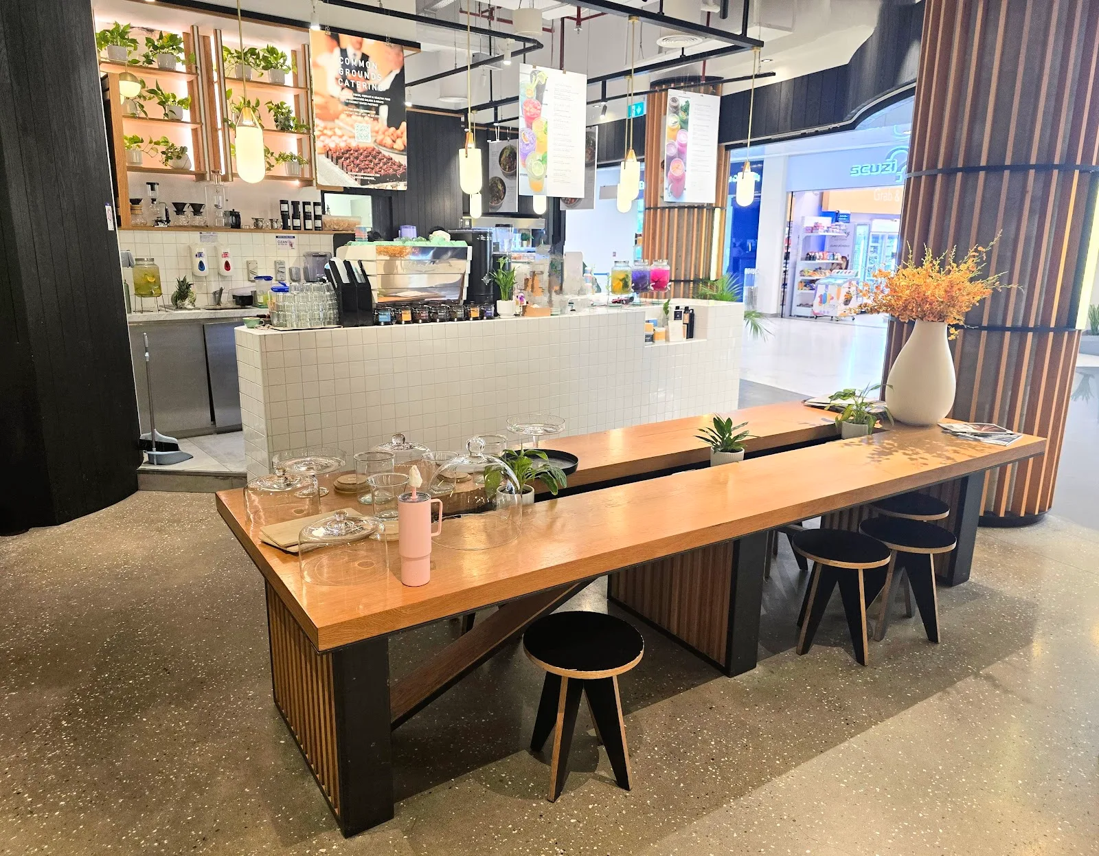 Long communal wooden table by the tiled coffee bar