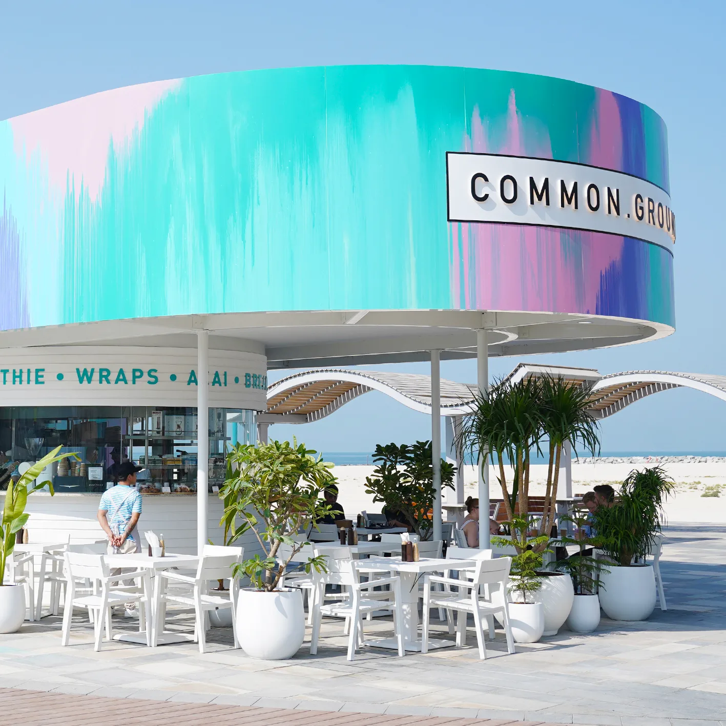 Common Grounds JLT painted lakeside kiosk with outdoor seating and the espresso, smoothie, wraps and breakfast menu band