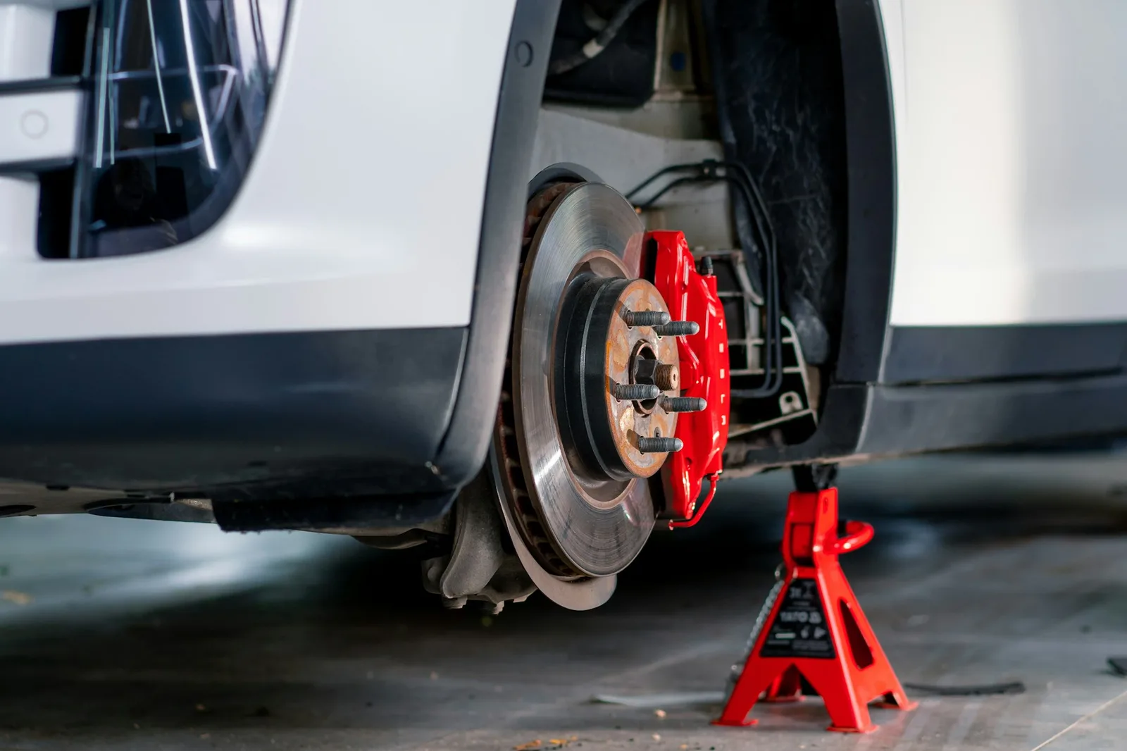 Brake disc and red caliper with the car on a jack stand