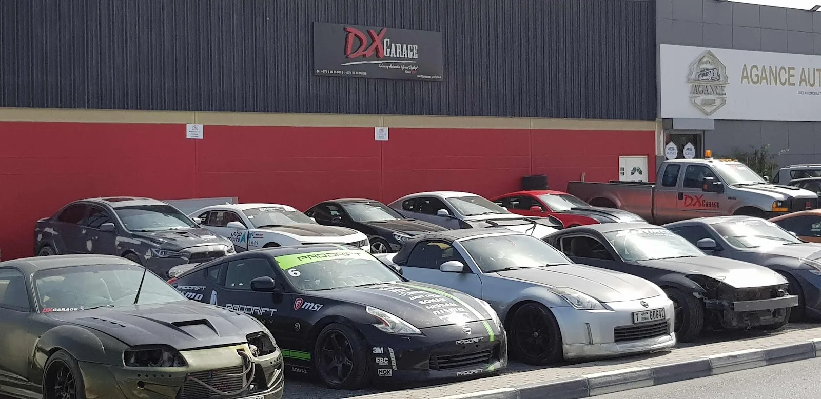 A row of drift and project cars parked at DX Garage