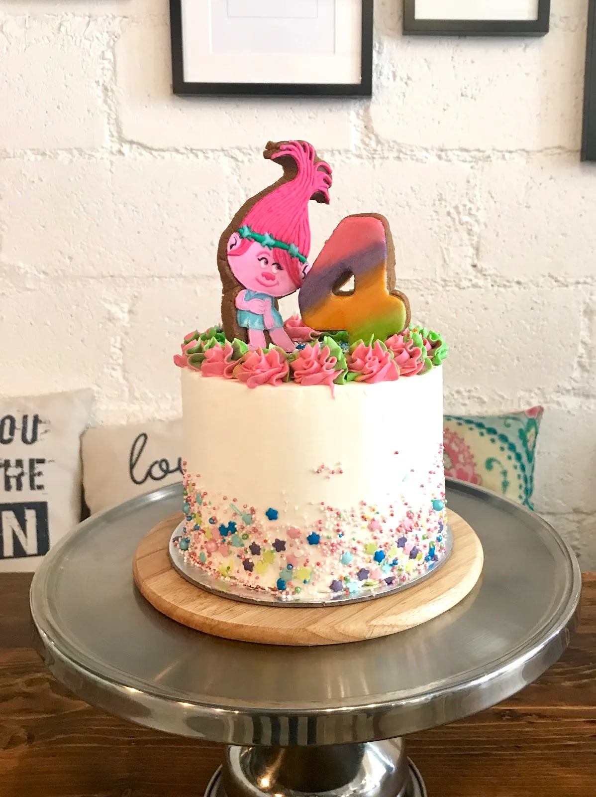 White buttercream birthday cake with a character topper, sprinkles and a number four
