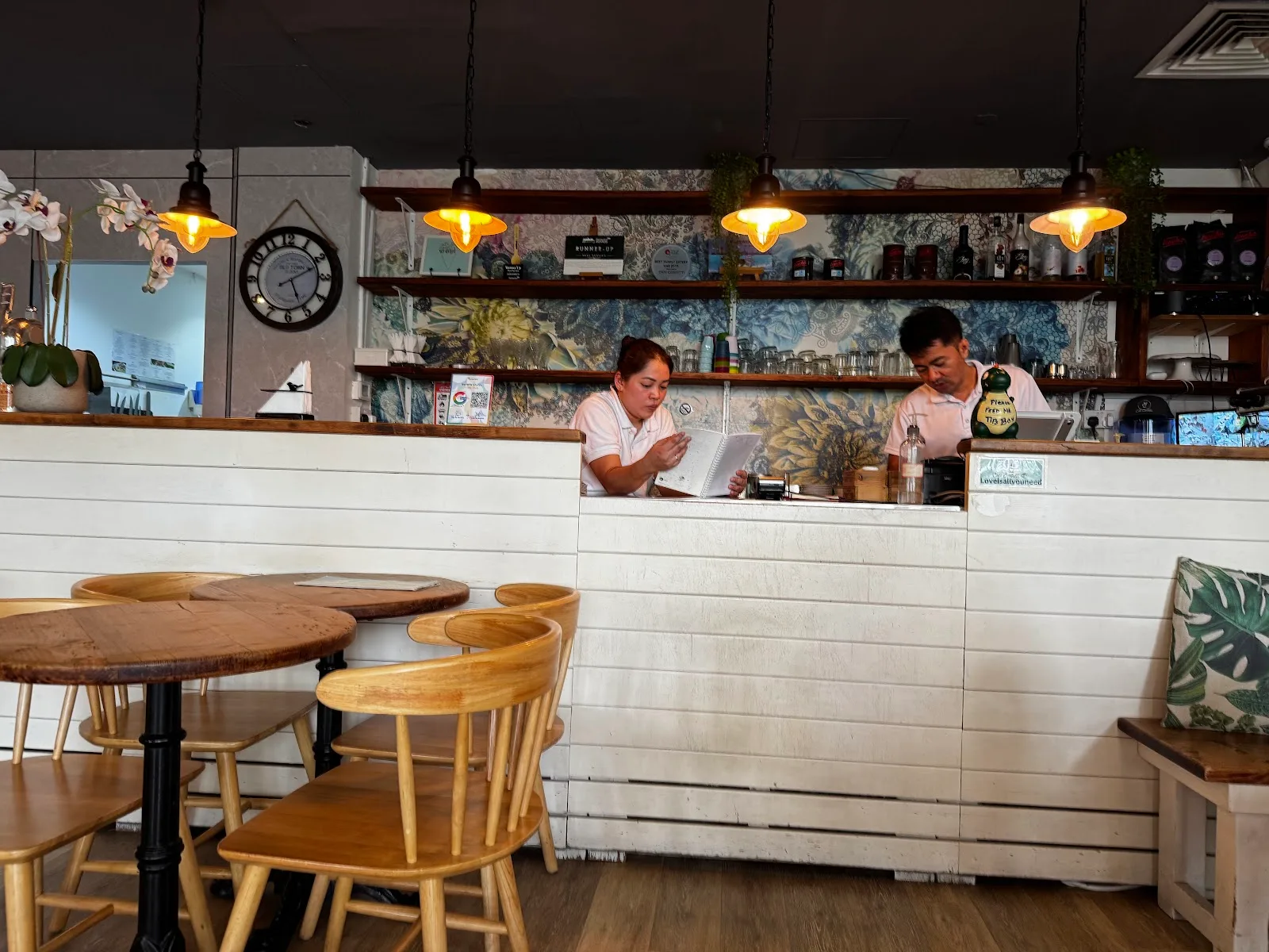 Café counter with floral-tiled wall and staff preparing orders