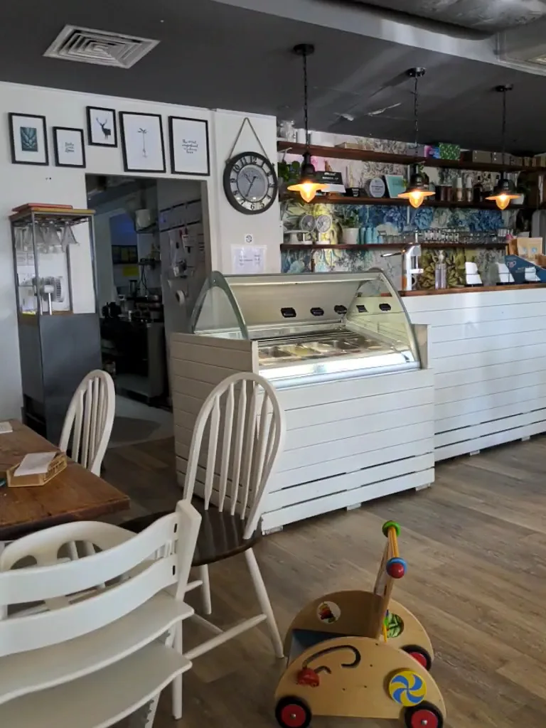 Gelato display counter beside white wooden chairs