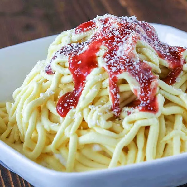 Spaghetti-eis — vanilla ice cream shaped like spaghetti with strawberry sauce and grated white topping
