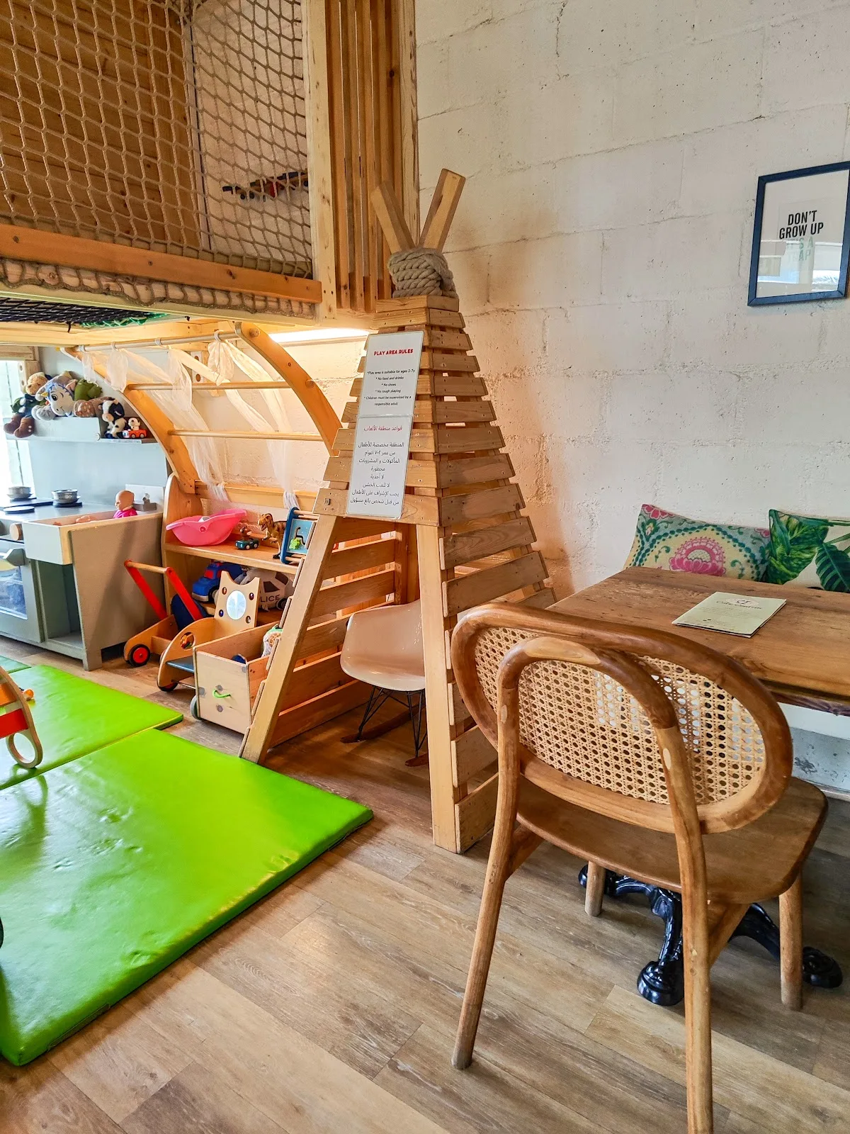 A wooden teepee play structure with toys and a cane chair