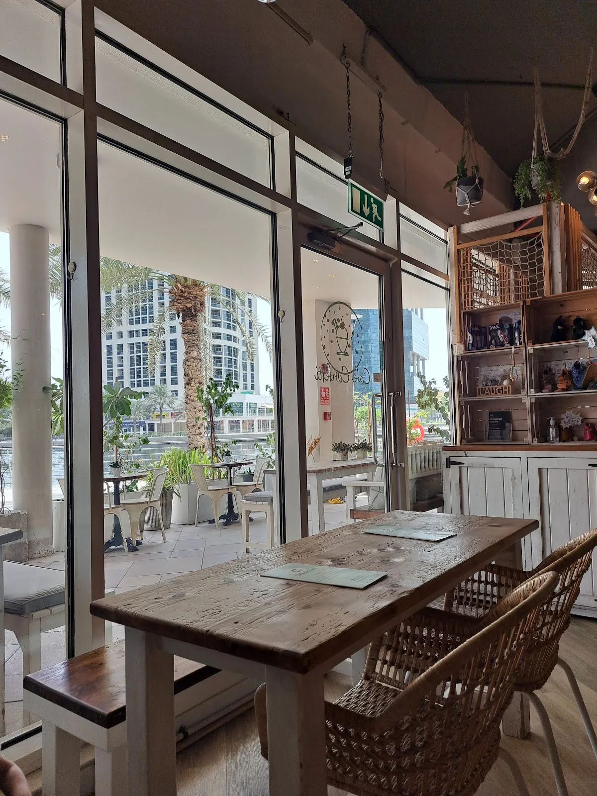 Lakeside table at Cafe Confetti with a view of the JLT towers and palm trees through the glass